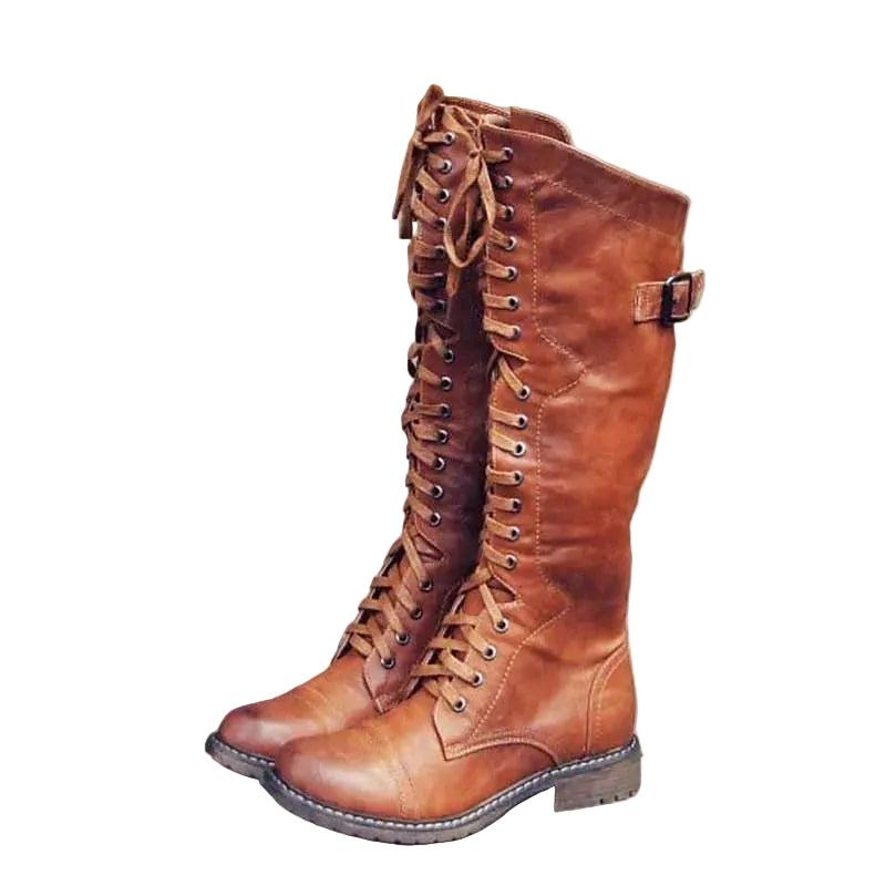 Bota alta marrón de inspiración ecuestre, con cordones frontales a lo largo de la caña, correa lateral con hebilla, punta redondeada y tacón bajo.