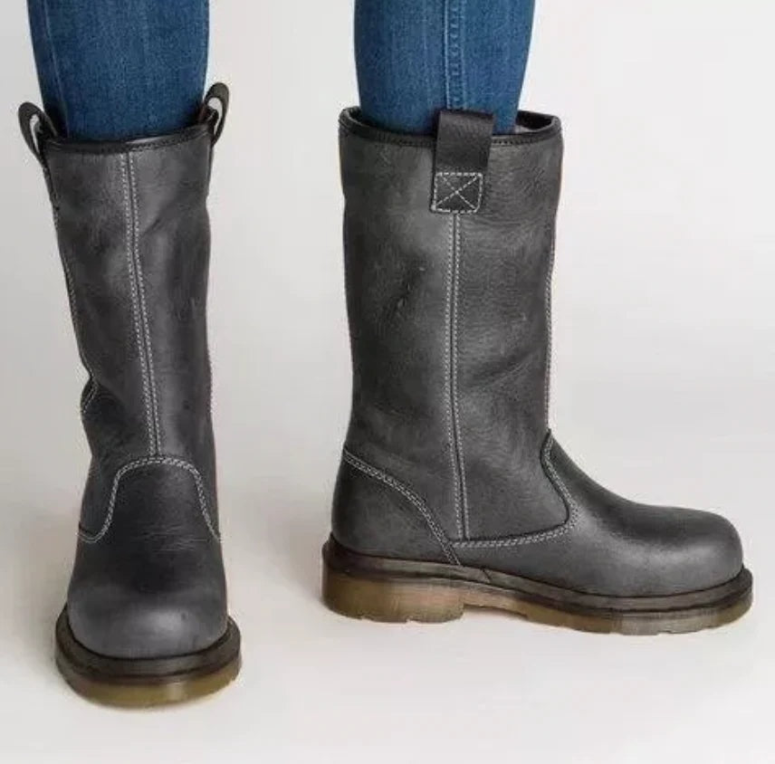 Botas altas gris oscuro de punta redonda, fotografiadas desde el frente y el lateral, con costuras claras, tiradores superiores y suela de perfil marcado.