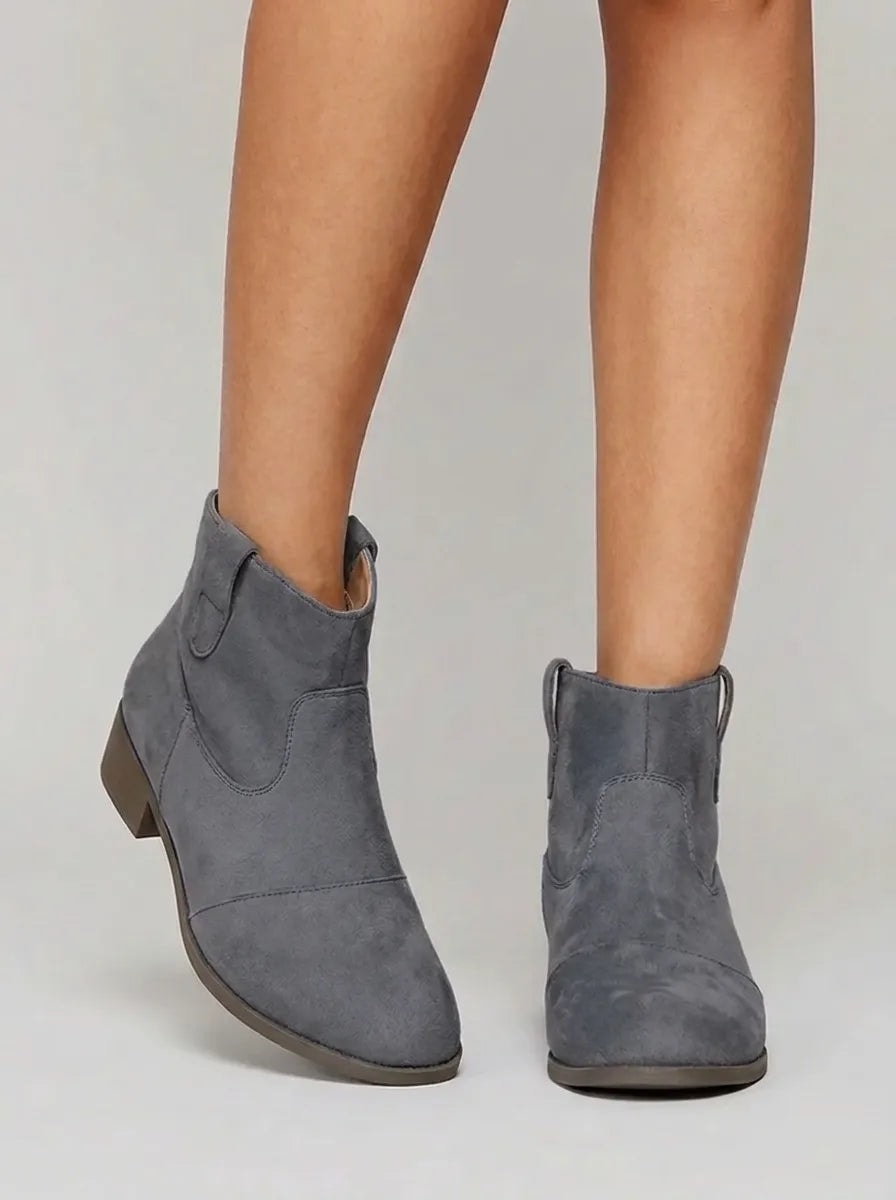 Botines Yolanda en color gris, vistos de frente y en ángulo para mostrar las costuras decorativas y el tacón bajo.