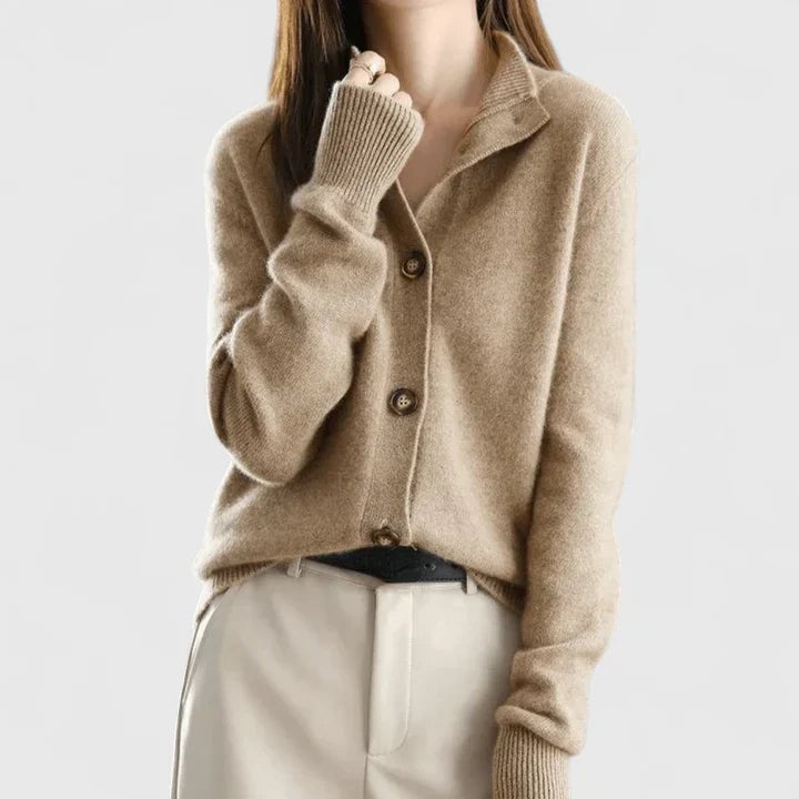 Cárdigan beige de cuello abierto con botones frontales y mangas largas, combinado con pantalón claro.