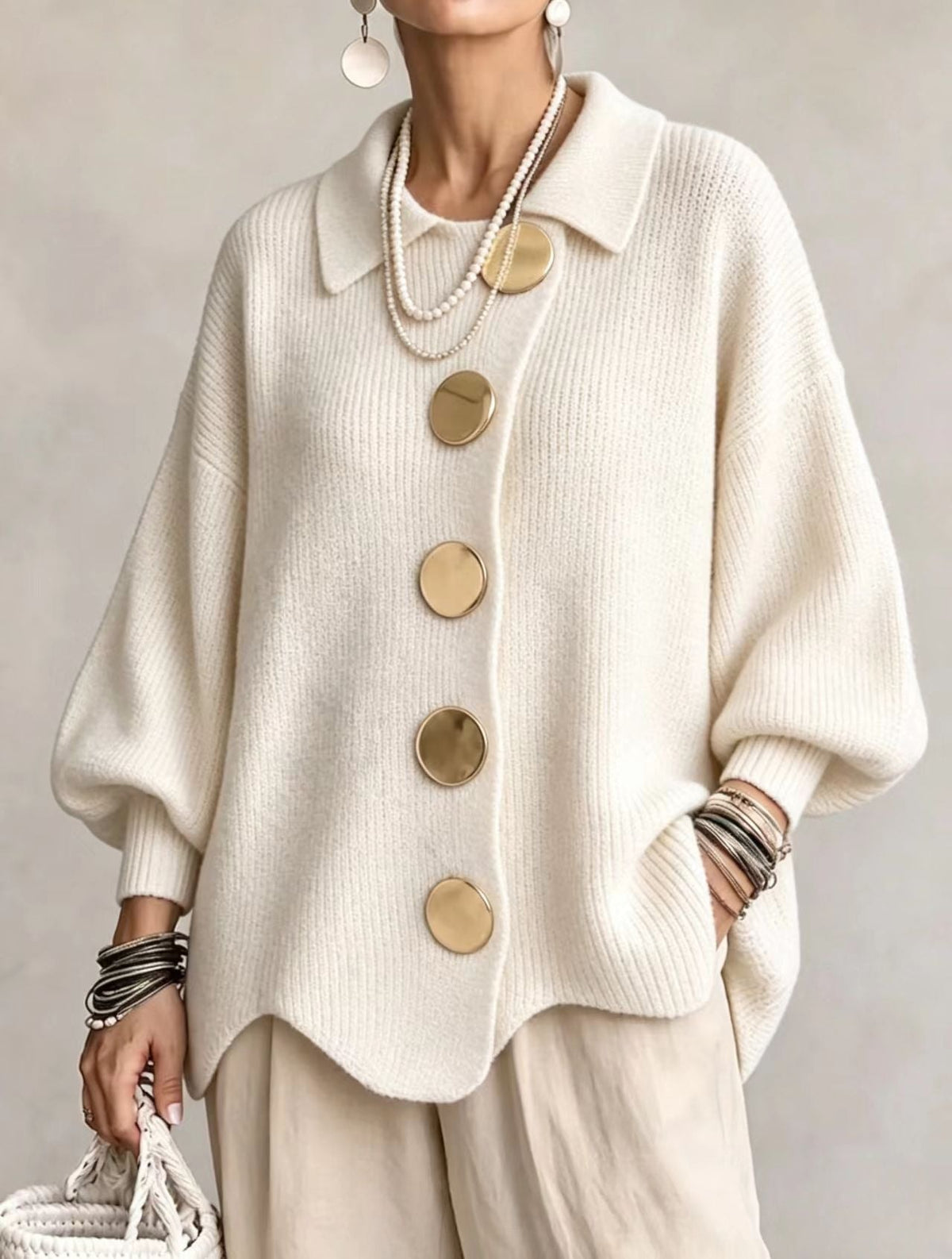 Cárdigan blanco roto con cuello, mangas amplias y cinco botones grandes, combinado con pantalones en tono claro.