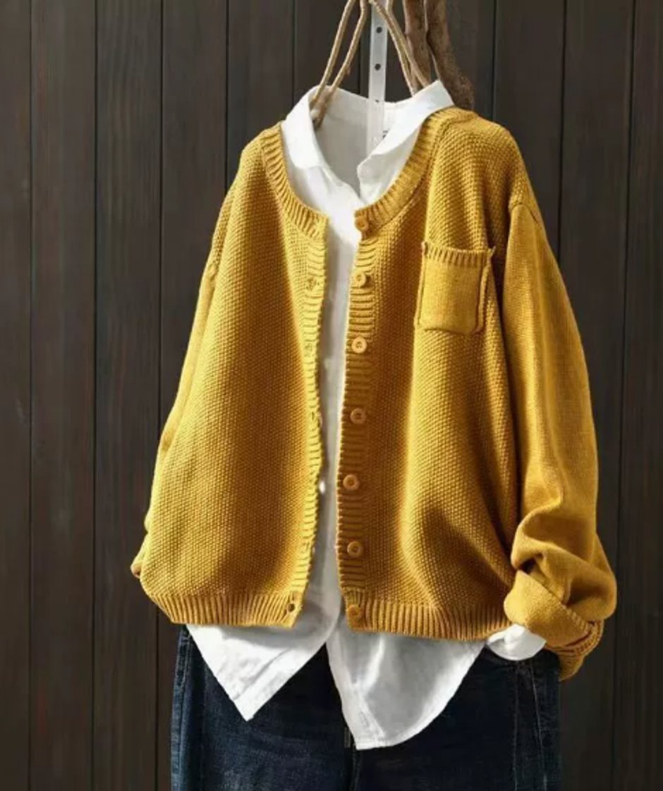 Cárdigan amarillo mostaza abotonado, con escote en V, bolsillo en el pecho y mangas largas sobre camisa blanca y vaqueros.
