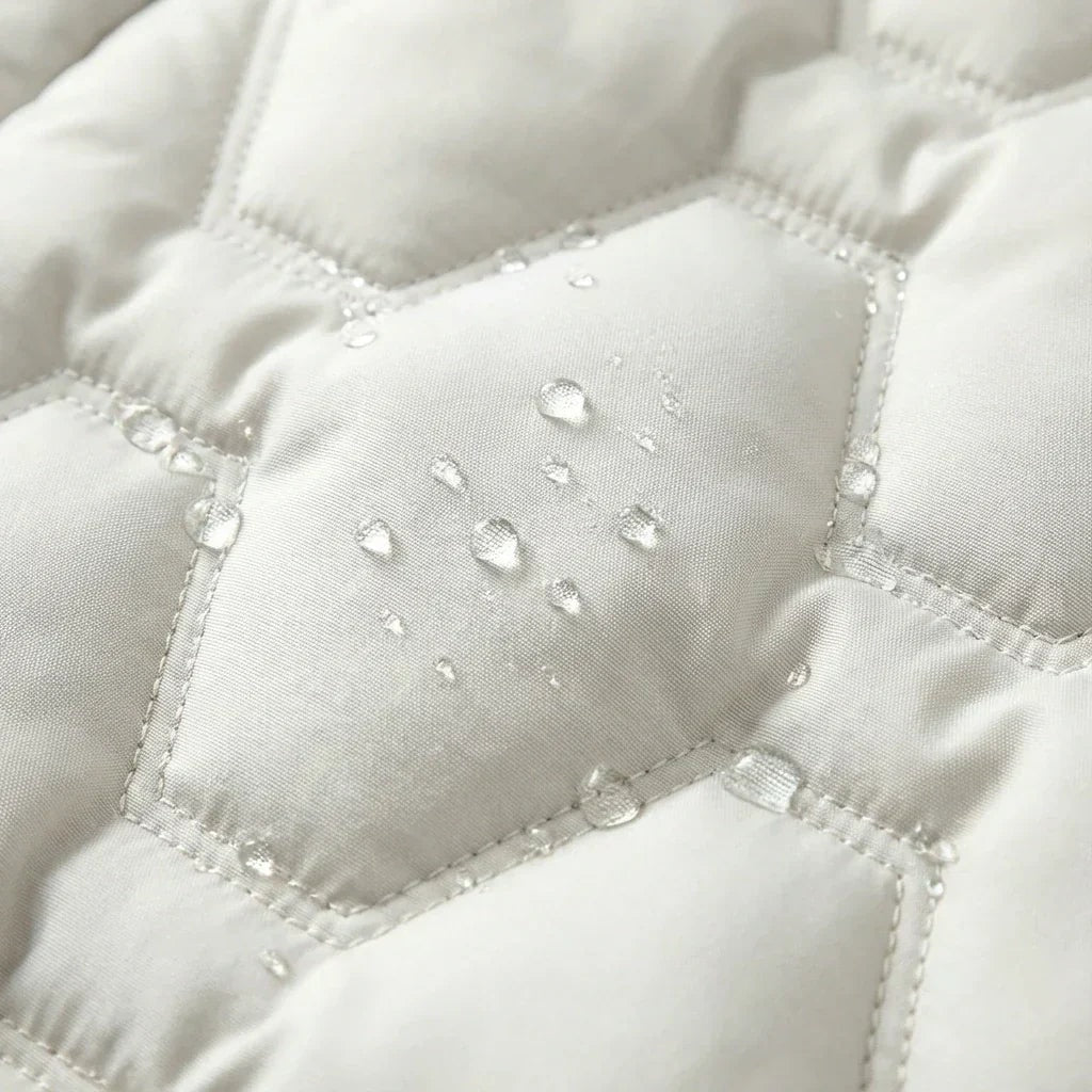 Primer plano del acolchado geométrico blanco con gotas de agua visibles entre las costuras.
