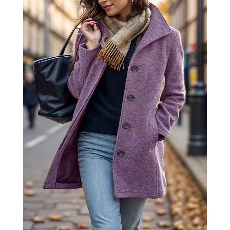 Abrigo de corte entallado en tono morado, con cuello de solapa, cierre frontal de botones y bolsillos laterales, combinado con vaqueros.
