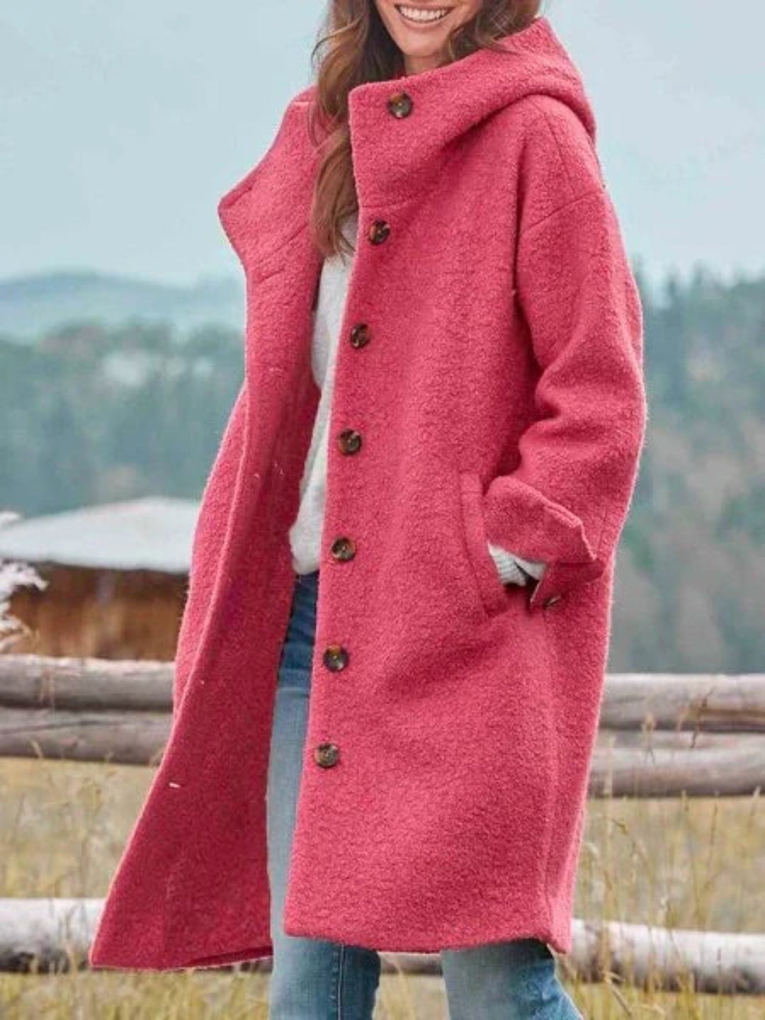Abrigo largo con capucha en color rosa, abotonado al frente y con bolsillos laterales, visto de cerca con una mano en el bolsillo.