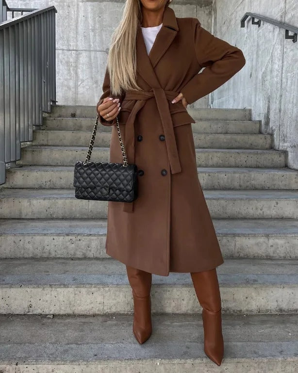 Abrigo largo marrón con cinturón ajustado en la cintura, doble botonadura y botas altas en un conjunto elegante.