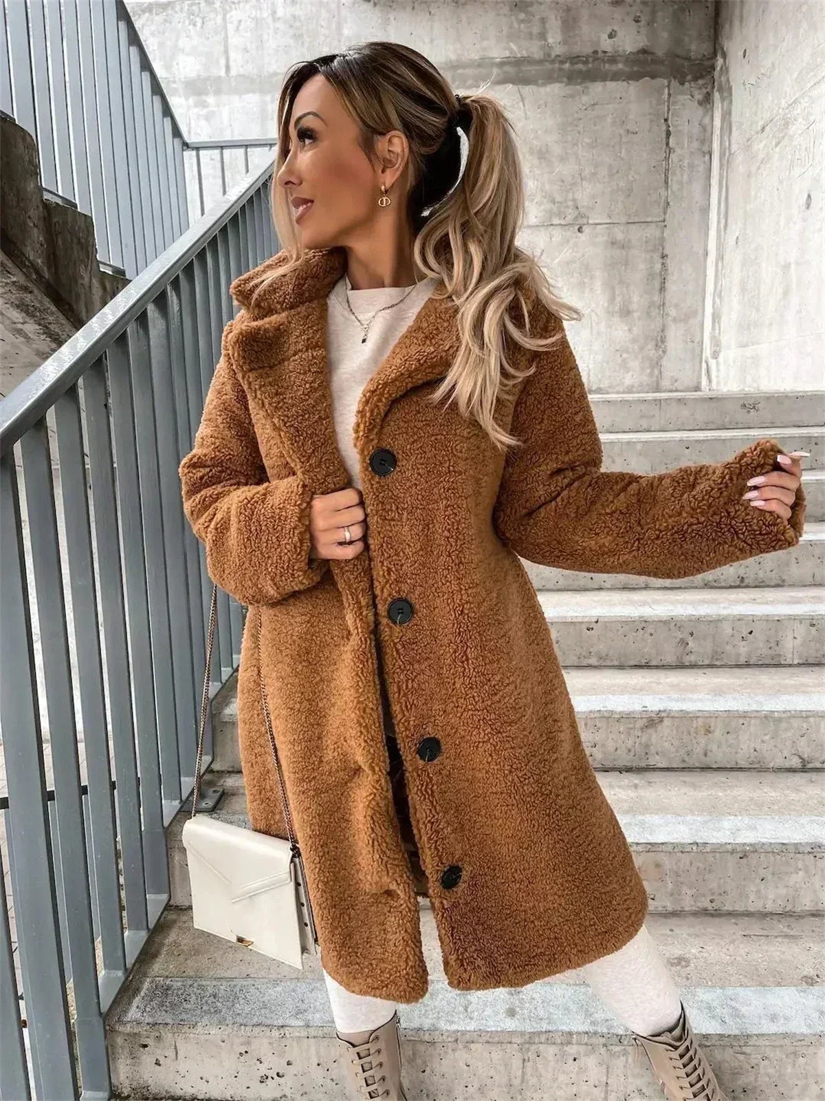 Abrigo teddy camel mostrado de cerca, con textura mullida, solapas amplias, mangas largas y botones negros en el frente.