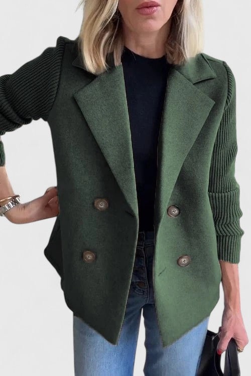 Blazer entallada verde oscuro con cuatro botones, solapas amplias y mangas acanaladas, acompañada de camiseta negra y vaqueros.