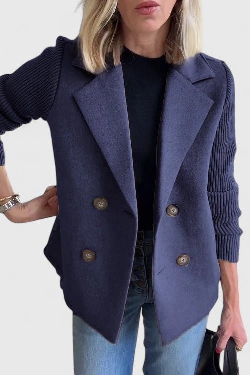 Blazer entallada azul marino con cuatro botones y mangas acanaladas, sobre camiseta negra y vaqueros claros.