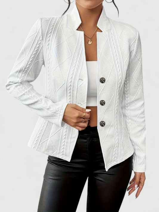 Blazer entallado blanco con textura geométrica, cuello con solapas y tres botones frontales, combinado con top blanco y pantalón negro.