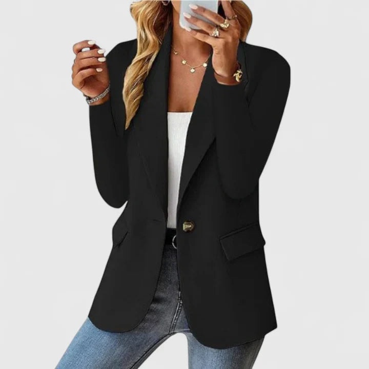 Blazer entallado negro de un botón, con solapas, mangas largas y bolsillos con solapa, combinado con camiseta blanca y vaqueros.