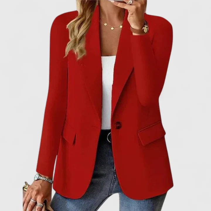 Blazer entallado rojo de un botón, con mangas largas, solapas y bolsillos con solapa, combinado con camiseta blanca y vaqueros.