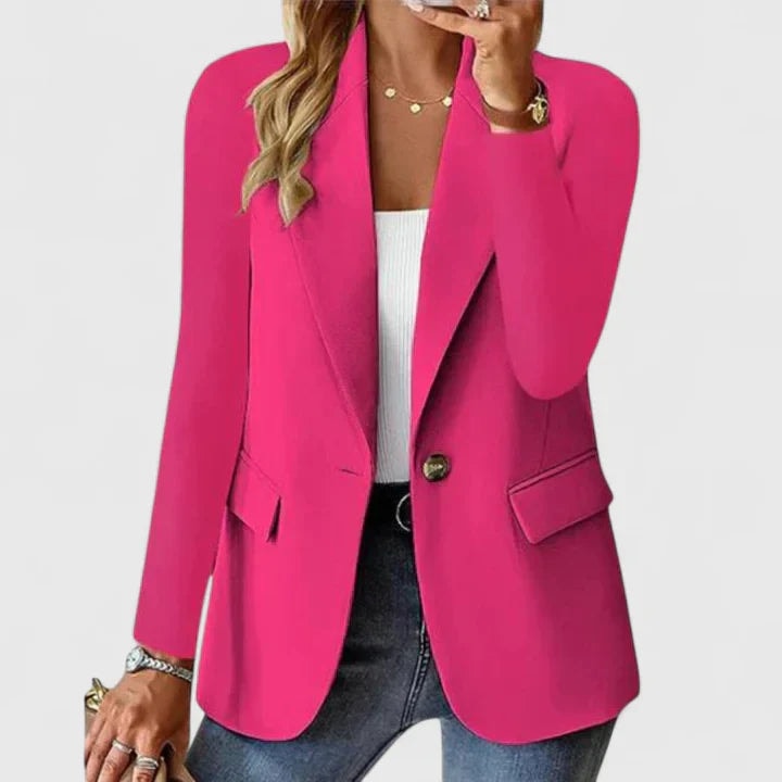 Blazer entallado fucsia de un botón, con silueta estructurada, solapas y bolsillos con solapa, combinado con vaqueros.