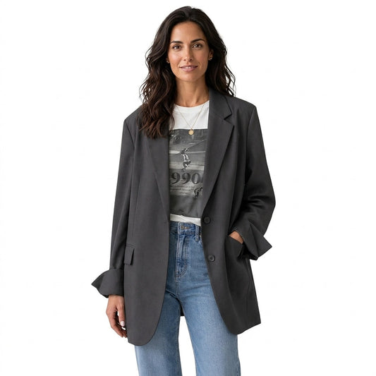 Blazer oversize gris oscuro con solapas clásicas, dos botones frontales y bolsillos, combinado con camiseta estampada y vaqueros.