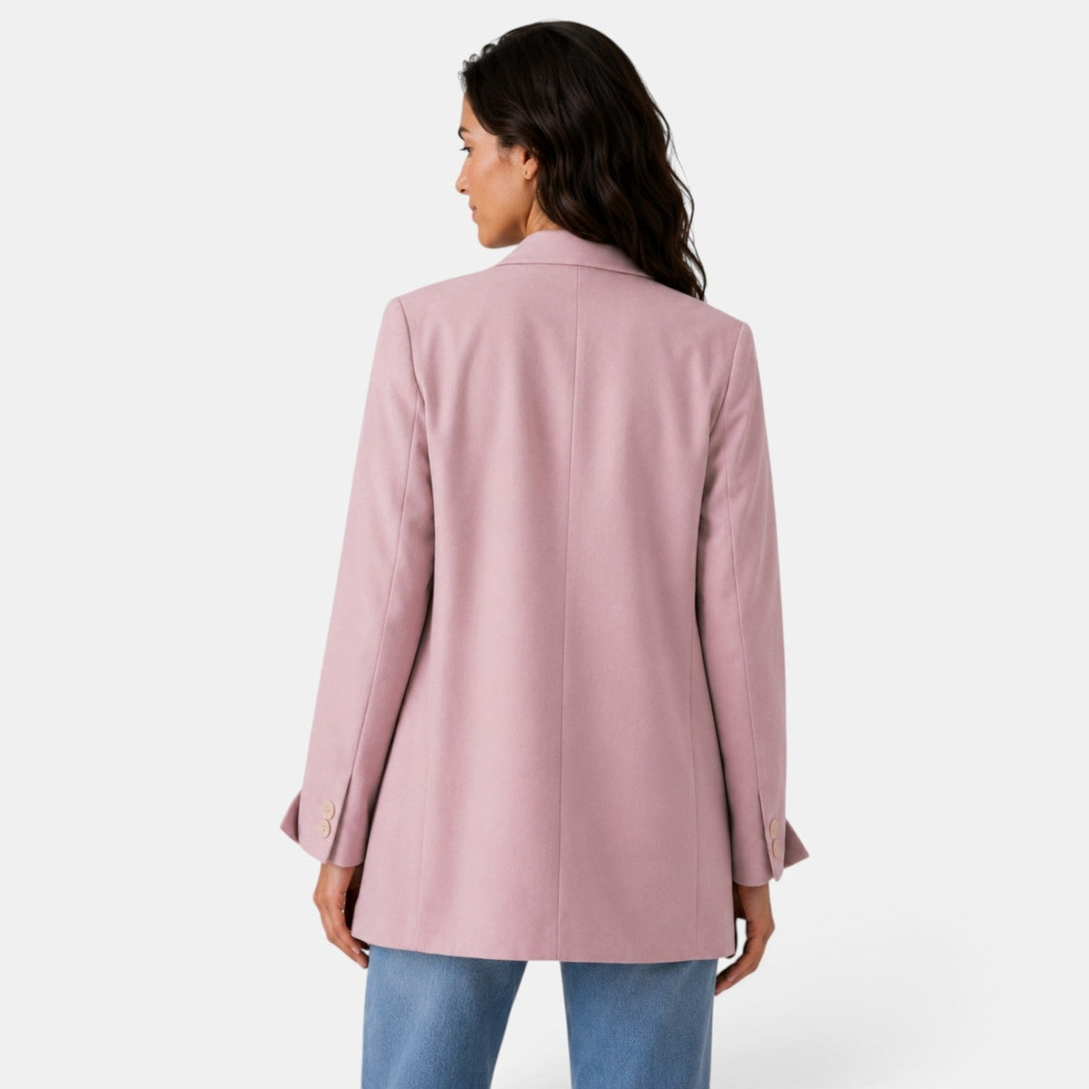Vista trasera del blazer oversize rosa claro, mostrando la costura central, el largo amplio y los detalles abotonados de los puños.
