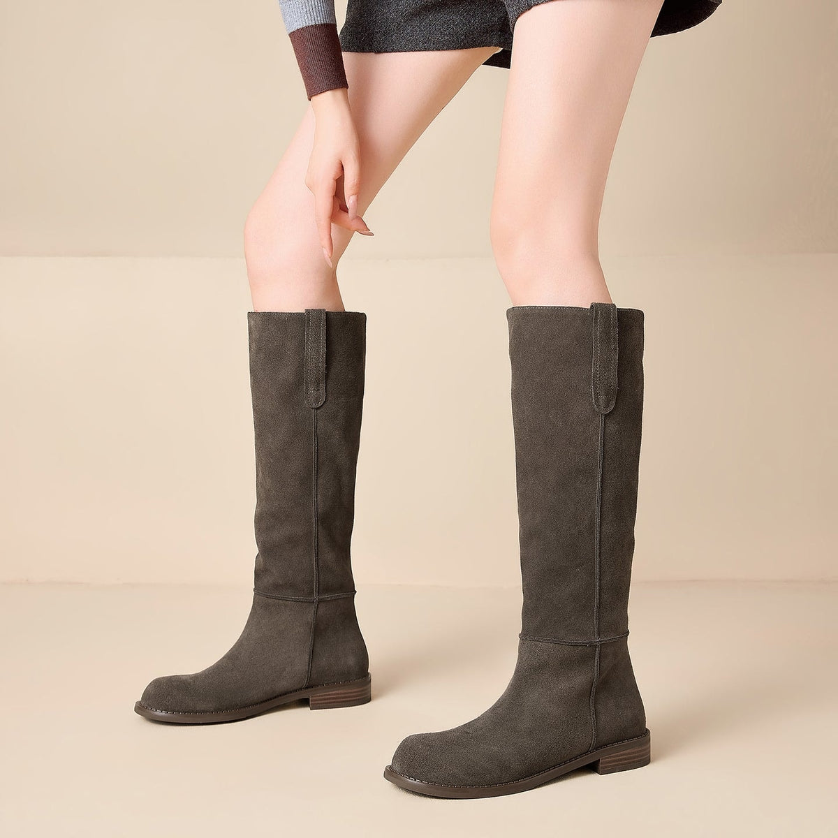 Botas altas de mujer en color gris oscuro, vistas de frente con caña hasta la rodilla, costuras verticales y suela plana.