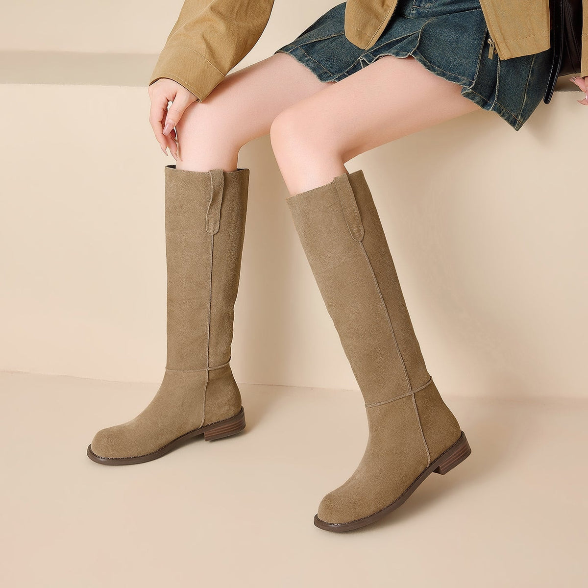 Modelo sentada con las botas altas marrón claro, destacando la caña recta y las costuras verticales.
