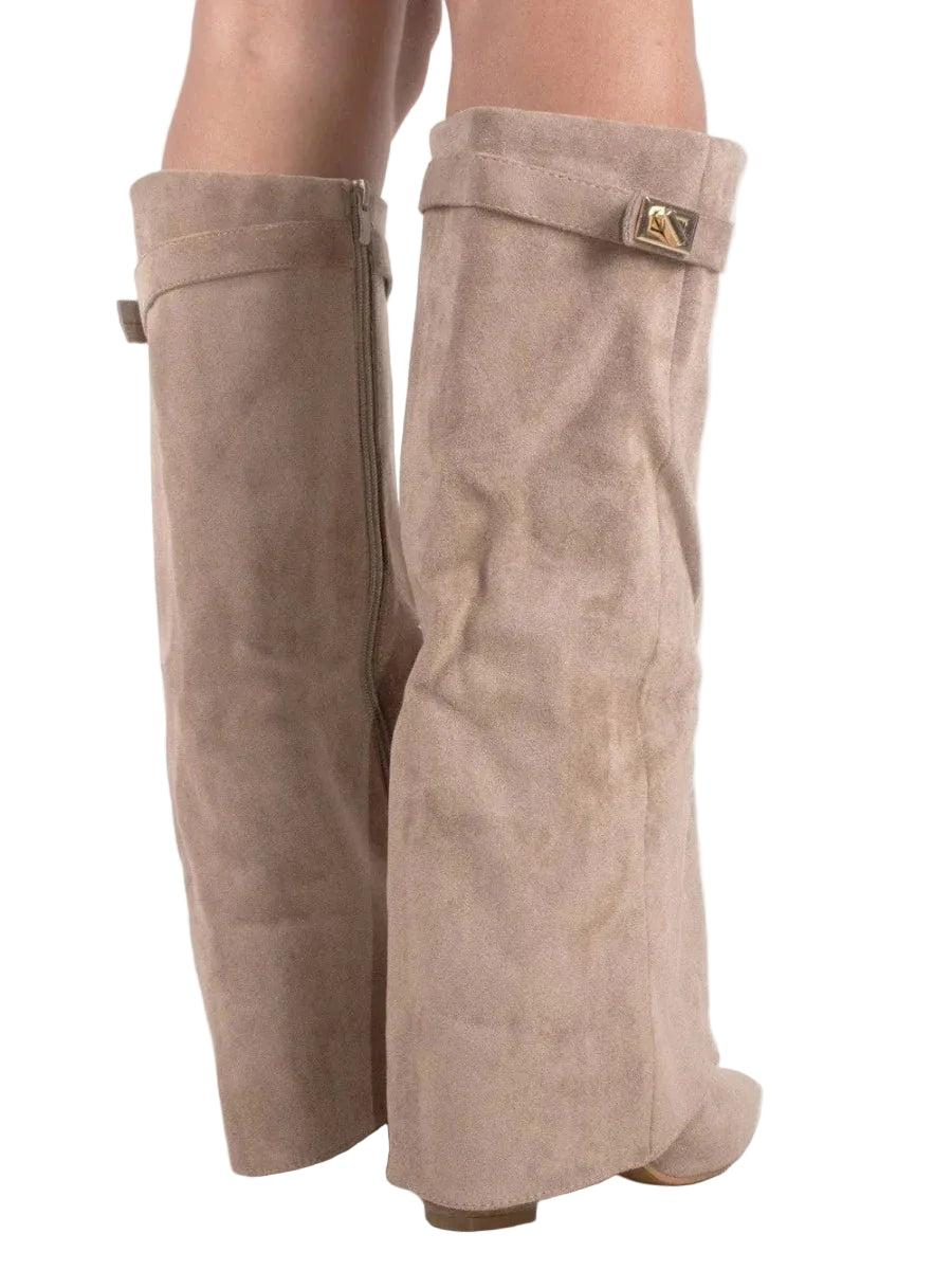 Botas altas en tono beige claro, mostradas de perfil posterior con cremalleras laterales y solapas decorativas.