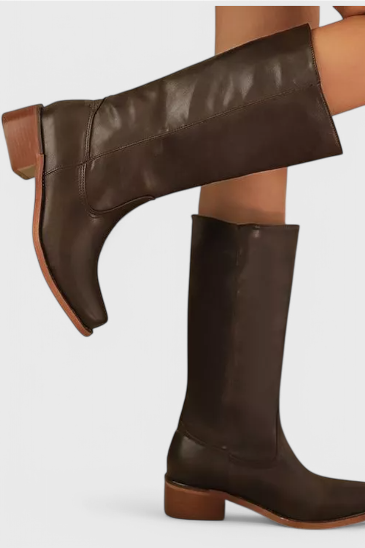 Bota alta marrón oscuro mostrada de perfil y otra suspendida en diagonal, con tacón bajo y caña recta.