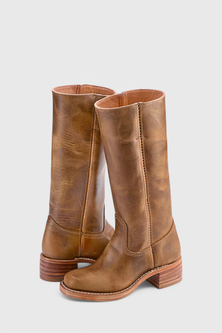 Dos botas altas en tono marrón cálido, superpuestas en vista de tres cuartos y con tacones bajos estriados.