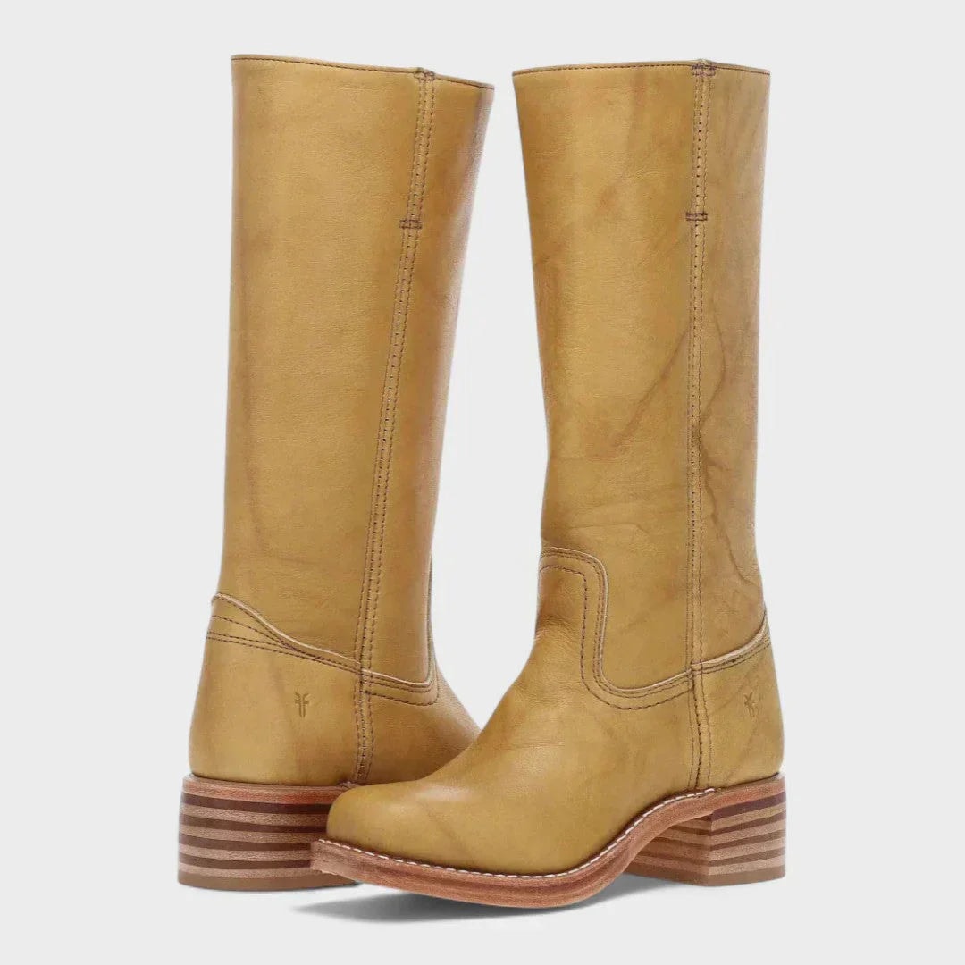 Botas altas color mostaza con caña lisa, detalles de costura en el empeine y tacón bajo de acabado estratificado.