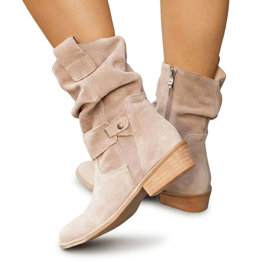 Botas de media caña en tono beige claro, con caña fruncida, correa decorativa en el tobillo y tacón ancho de acabado madera, mostradas desde un ángulo cruzado.