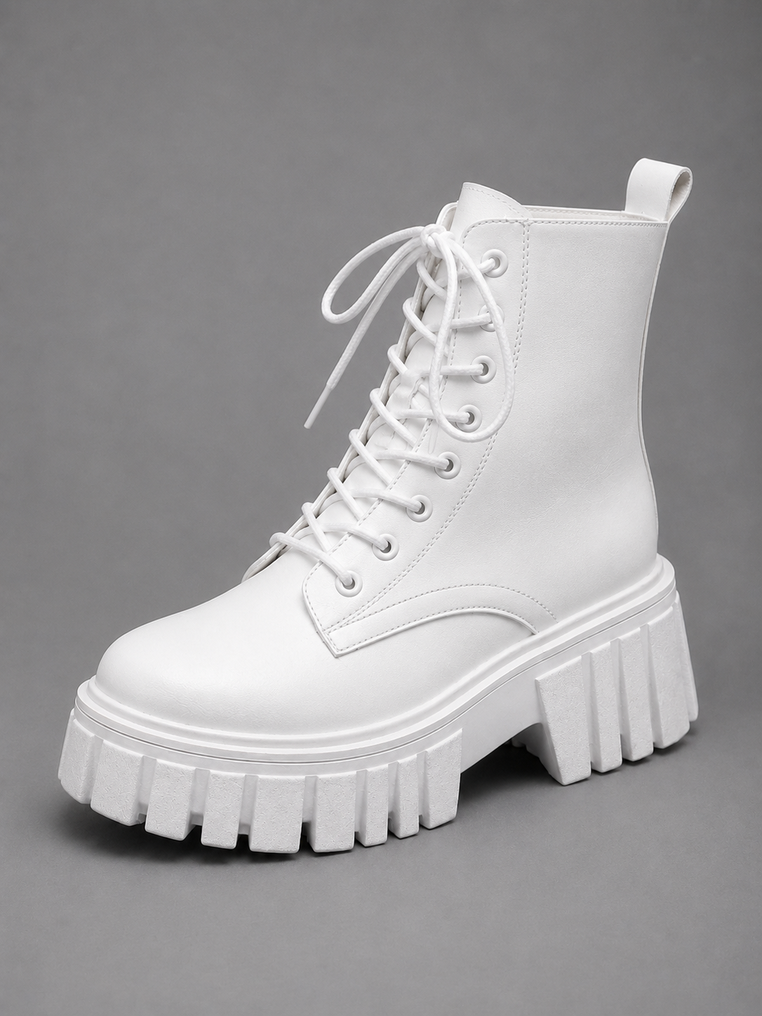 Bota militar blanca de plataforma con cordones, presentada en tres cuartos, con suela dentada y tirador en la parte posterior.