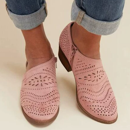 Botines bajos rosas con calado decorativo en ondas y motivos florales, mostrados puestos con vaqueros remangados.