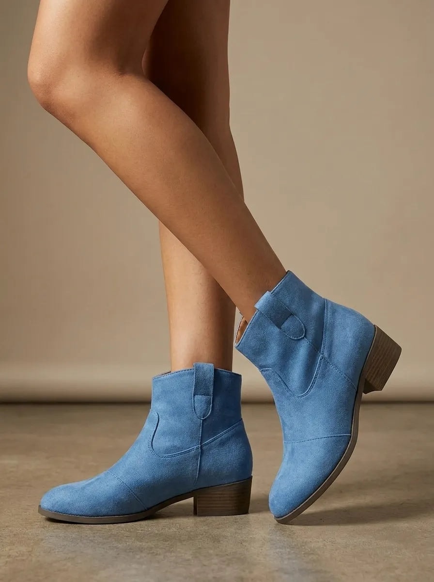 Botines Yolanda azules mostrados en una pose lateral, donde se aprecia la punta redondeada y el tacón bajo.