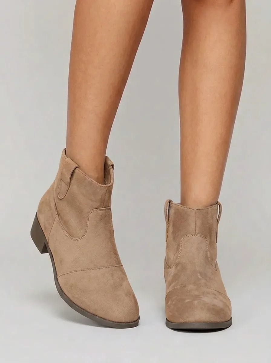 Botines western Yolanda en color beige, con caña al tobillo, punta redondeada y tacón bajo.