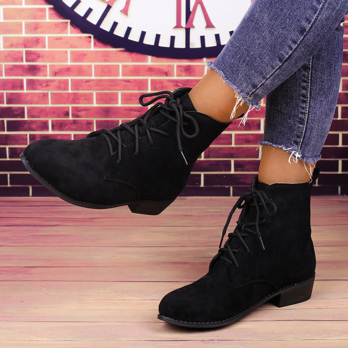 Botines negros con cordones llevados con vaqueros, en una vista lateral que resalta el perfil al tobillo y el tacón bajo.