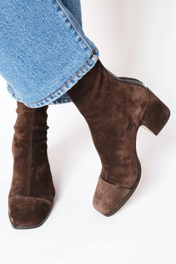 Botines marrones de punta cuadrada y tacón de bloque vistos de perfil, combinados con vaqueros de pierna recta.