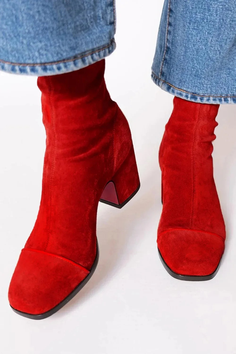 Botines rojos de tacón ancho vistos desde arriba, destacando las punteras lisas y el ajuste fruncido del tobillo.