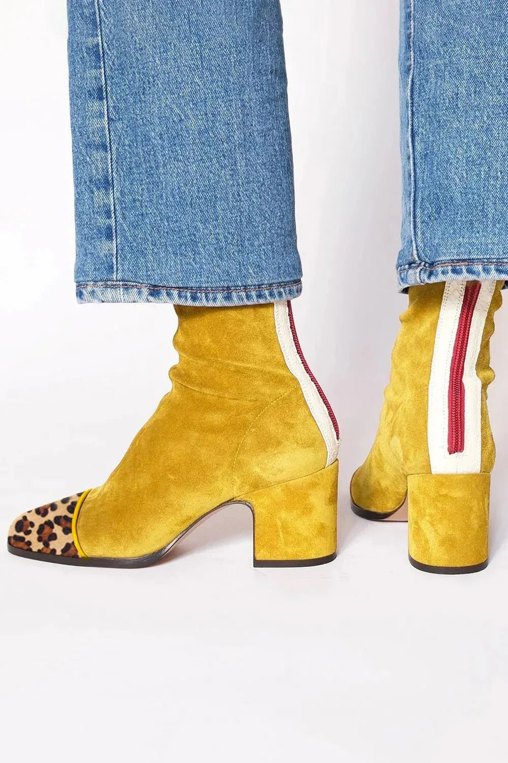 Botines amarillos de tacón ancho con puntera de leopardo y vista posterior de la cremallera roja.