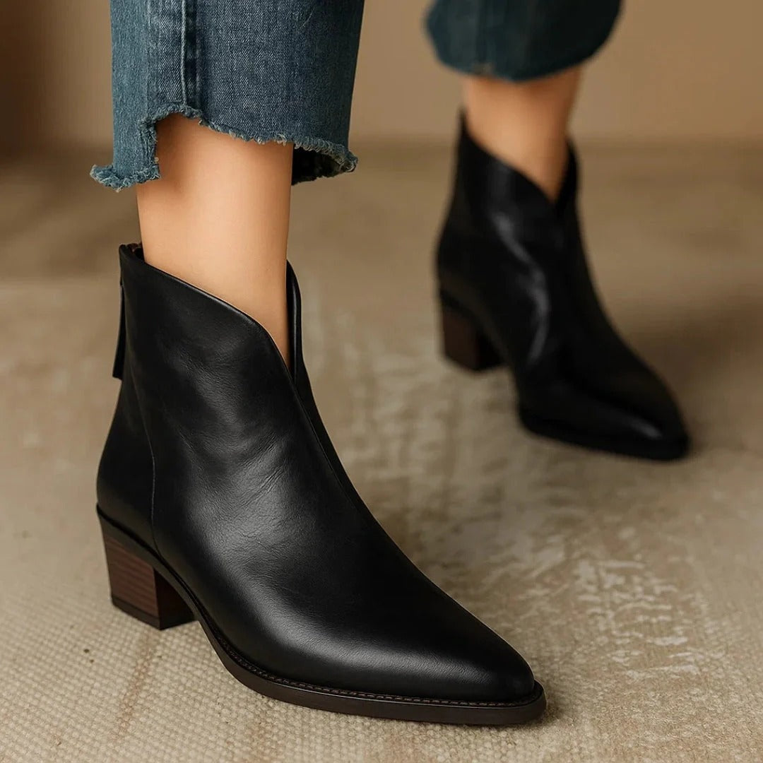 Botines negros de tacón bajo y punta afilada, mostrados en primer plano con otro botín al fondo y vaqueros cortos.