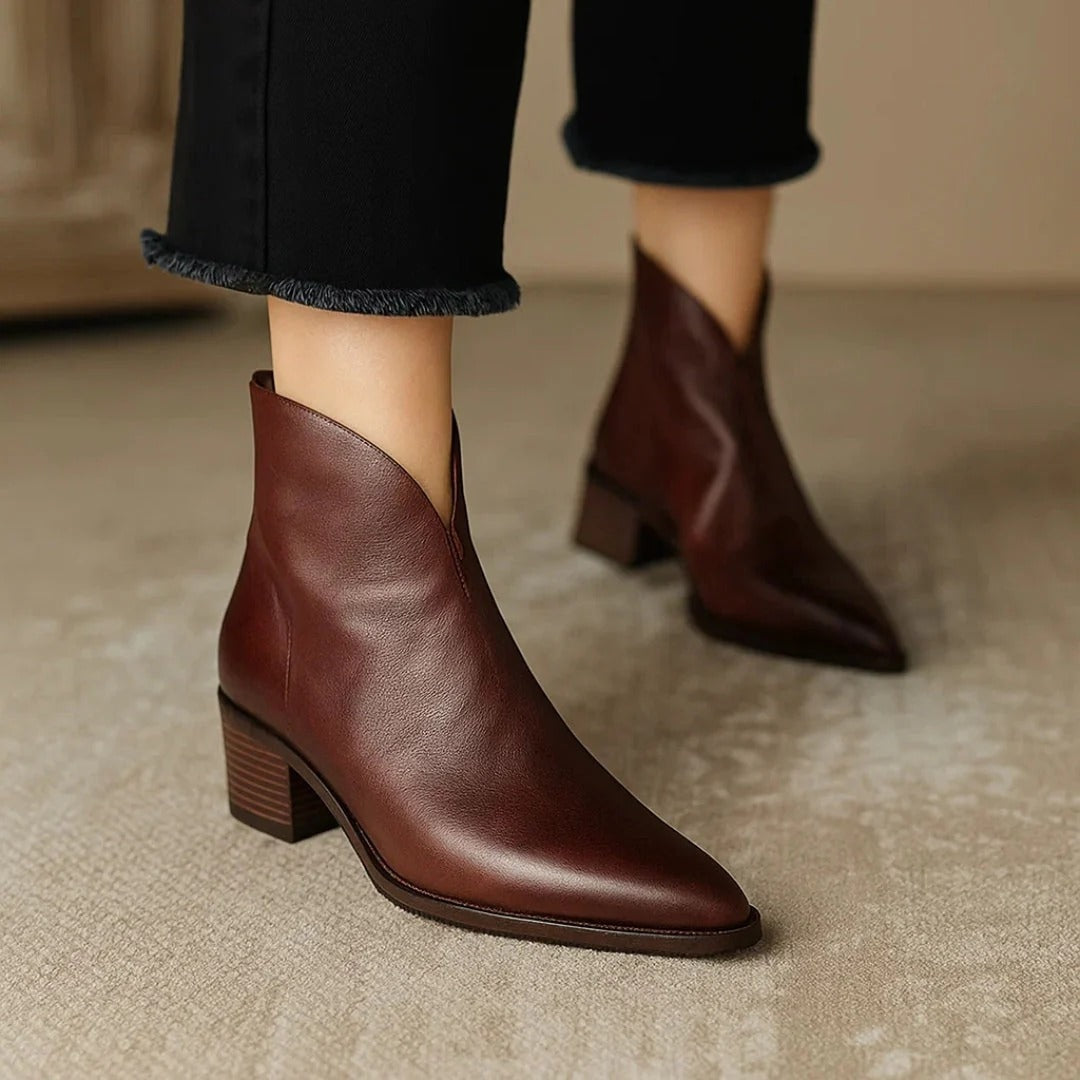 Botines marrones de líneas limpias, punta afilada y tacón bajo, combinados con pantalón negro de bajo desflecado.