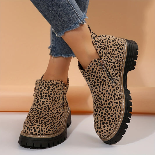 Botines planos de caña baja con estampado de leopardo, cremallera lateral y suela negra dentada, vistos en los pies con vaqueros.