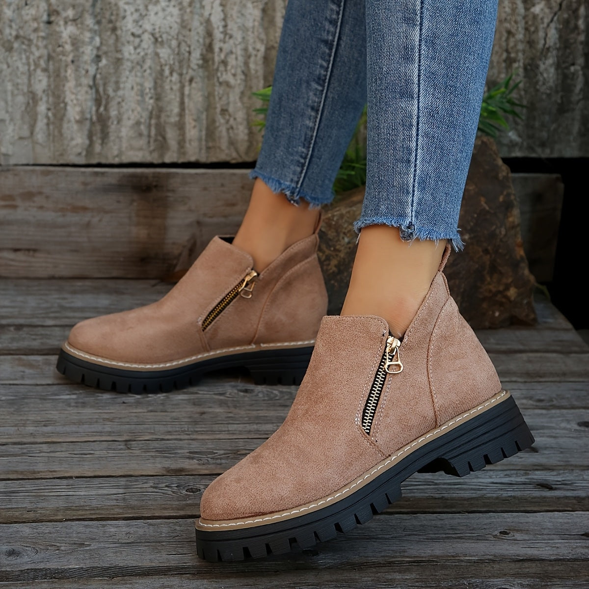 Botines en tono topo rosado con caña baja, cremalleras laterales y suelas negras dentadas, combinados con vaqueros.