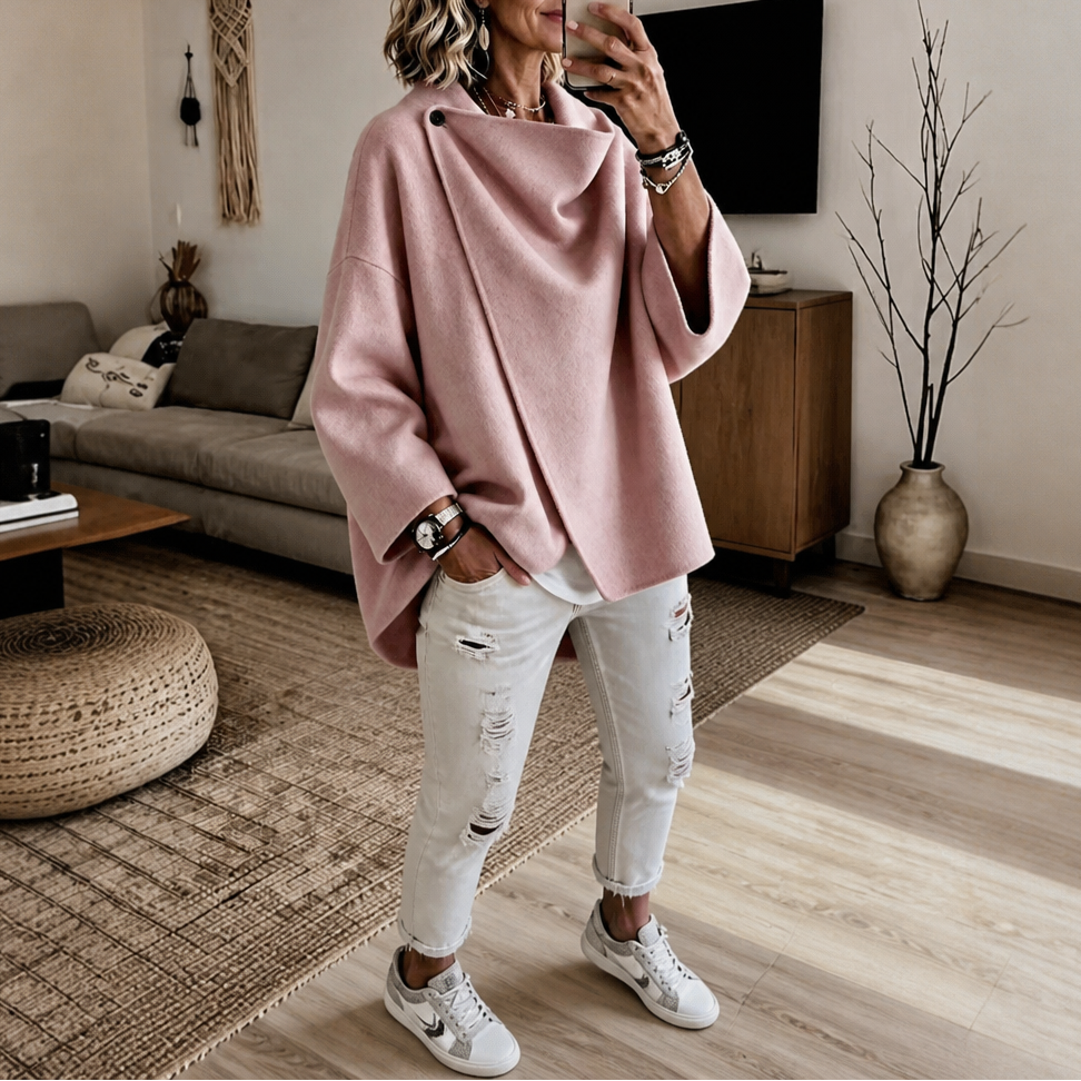 Capa chaqueta rosa empolvado con mangas amplias y silueta asimétrica, llevada con zapatillas.