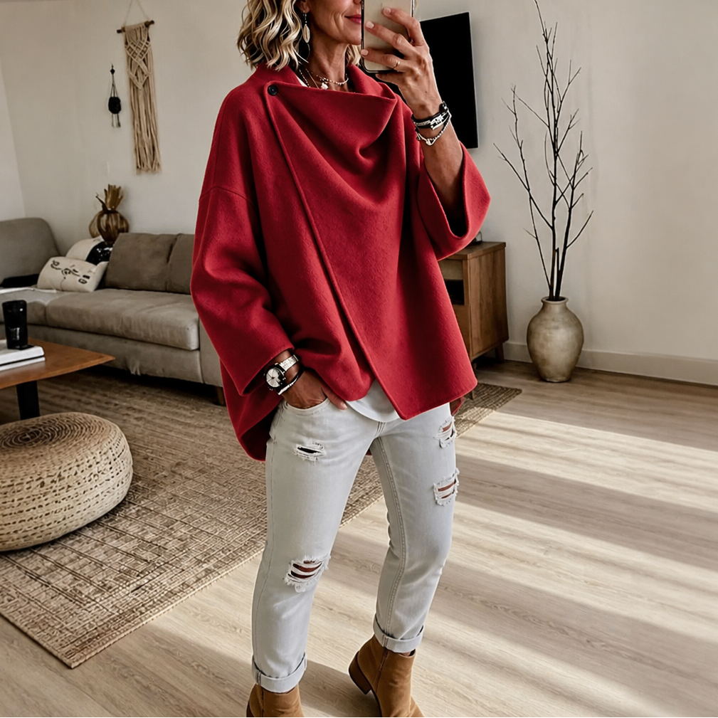 Capa chaqueta roja con cuello drapeado y largo asimétrico, combinada con vaqueros blancos y botines.