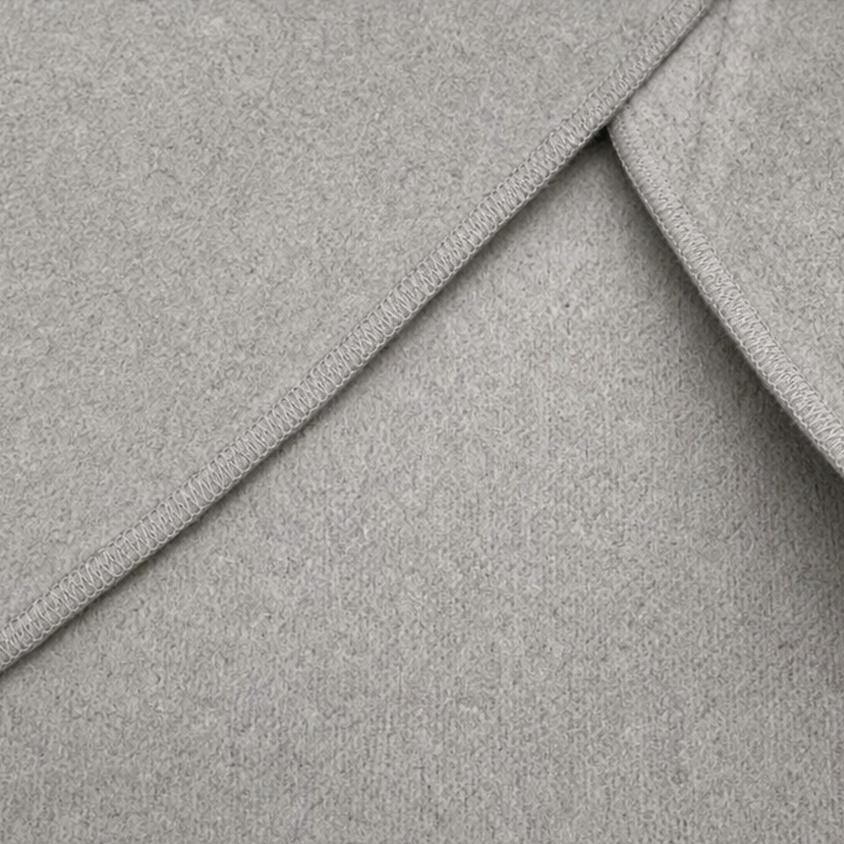 Detalle del acabado de los bordes y las costuras de la capa chaqueta gris claro.