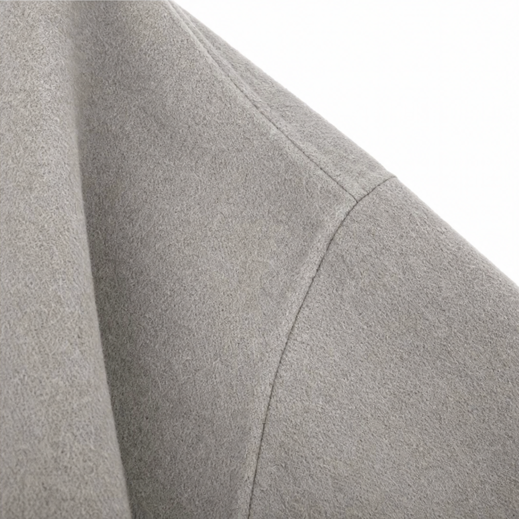Detalle de la costura en la manga amplia de la capa chaqueta gris claro.