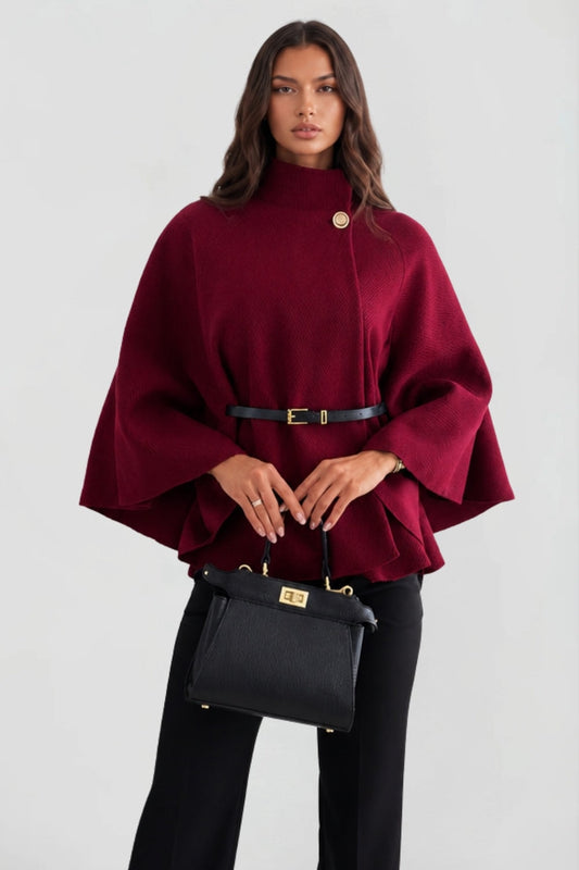 Capa burdeos de mujer con cuello alto abotonado, cinturón negro y mangas amplias, vista frontal con bolso negro.