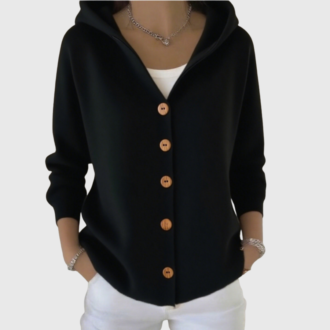 Cárdigan negro con capucha y botones de color madera, abierto en el cuello sobre una camiseta blanca.