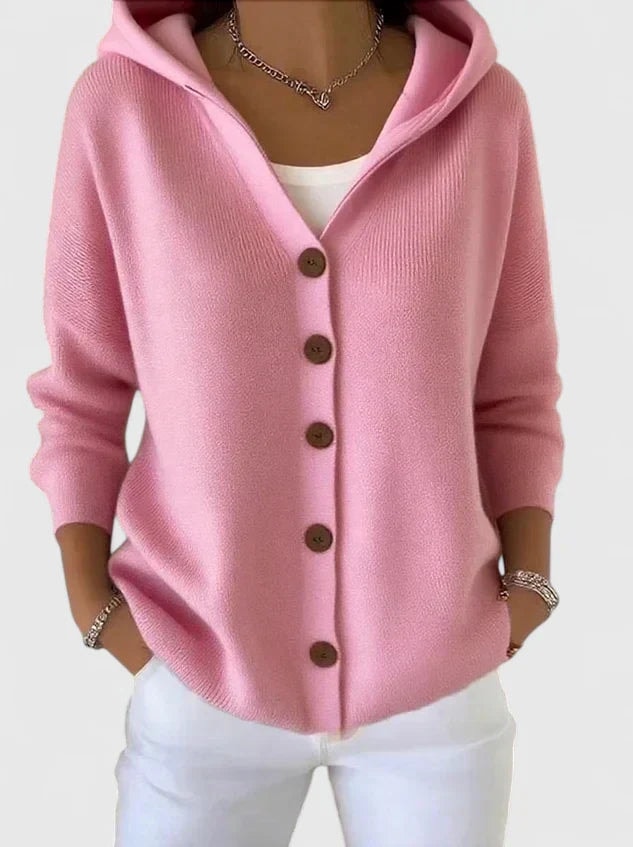 Cárdigan rosa con capucha y cinco botones marrones en la parte delantera, llevado sobre una camiseta blanca.