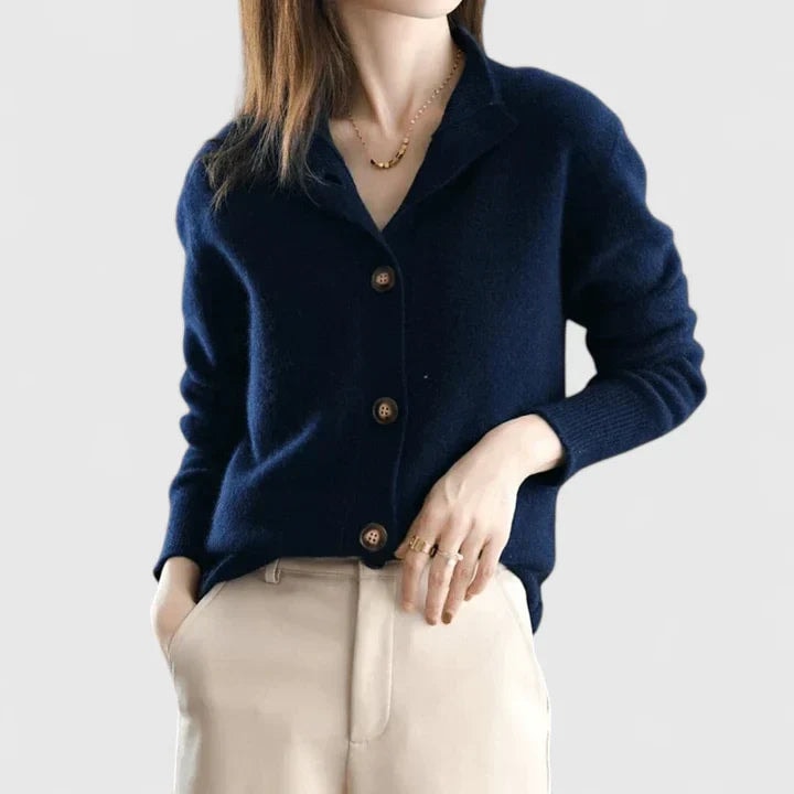 Cárdigan azul marino con cuello abierto, botones frontales y puños ajustados, llevado con pantalón beige.