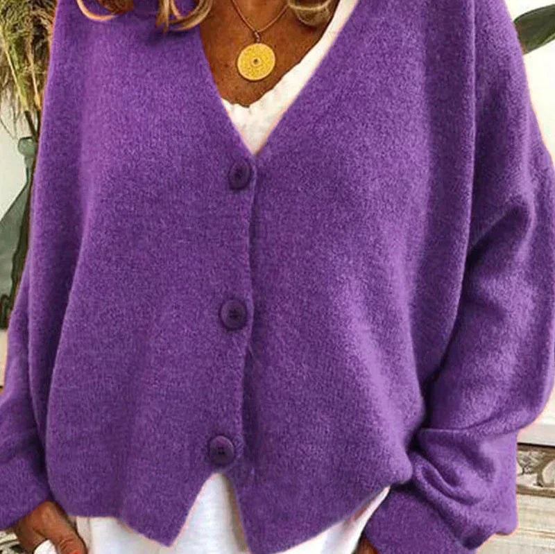Cárdigan morado de corte holgado, con tres botones visibles y mangas largas fruncidas en los puños.