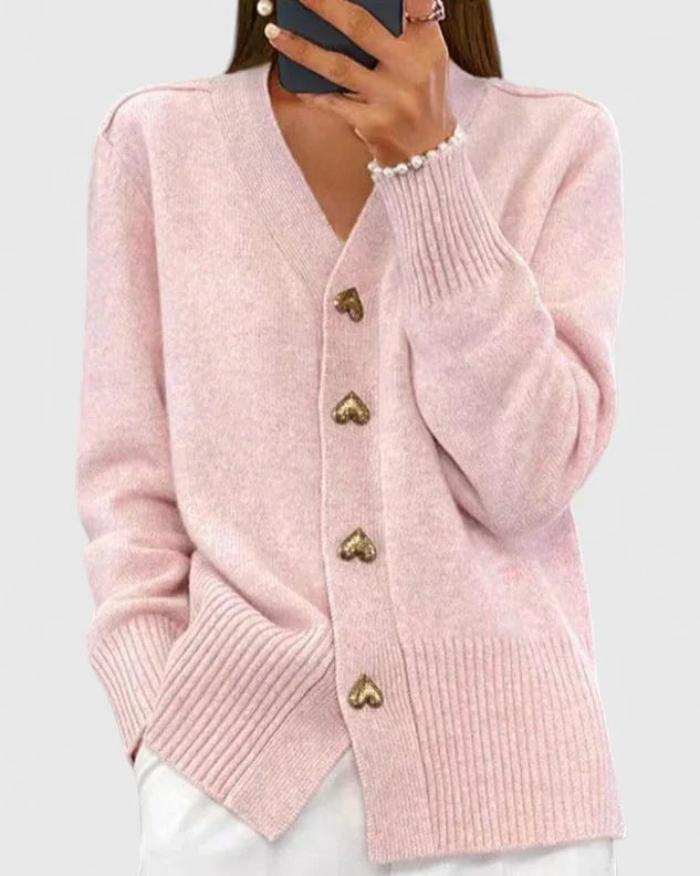 Cárdigan rosa claro con cierre frontal de botones de corazón, bolsillos delanteros y bajo de textura acanalada.