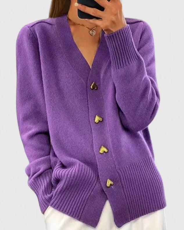 Cárdigan morado de corte holgado con cuello en V, cuatro botones de corazón y mangas ligeramente recogidas.