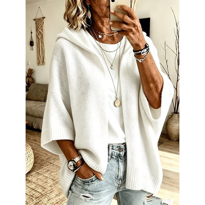Cárdigan holgado blanco con capucha y frente abierto, combinado con camiseta blanca y vaqueros claros.